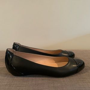 Black round toe flats with patent toe and covered heel.